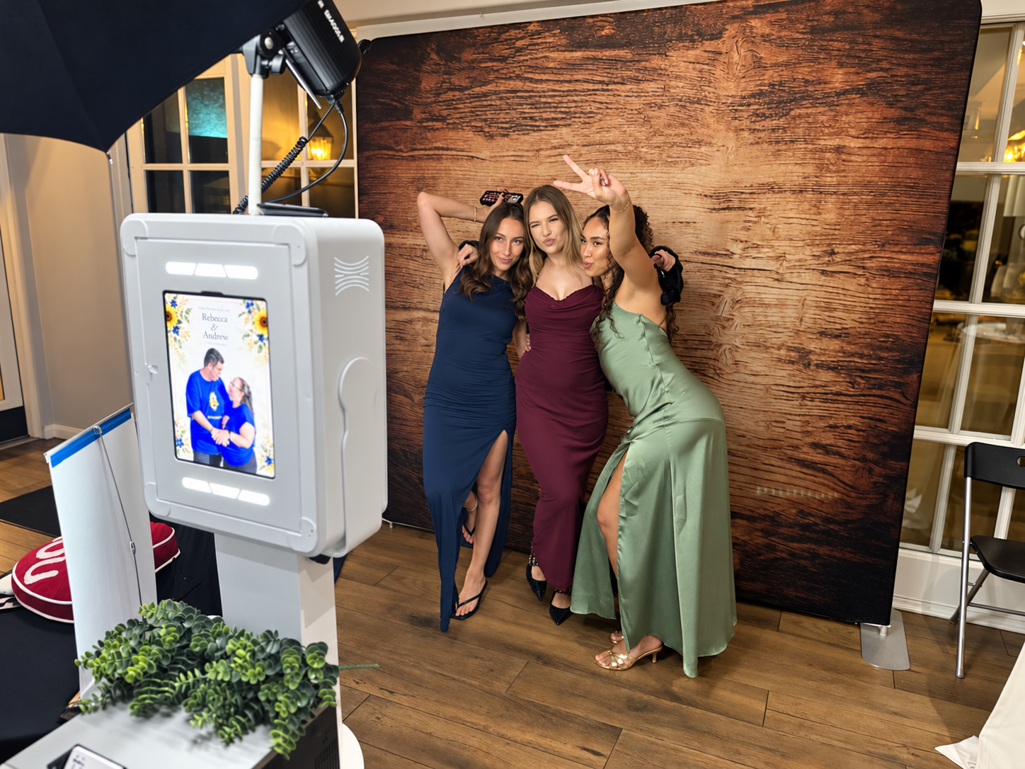 Behind the scenes: three guests posing in front of the backdrop with the Tinseltown Lux Booth beside them